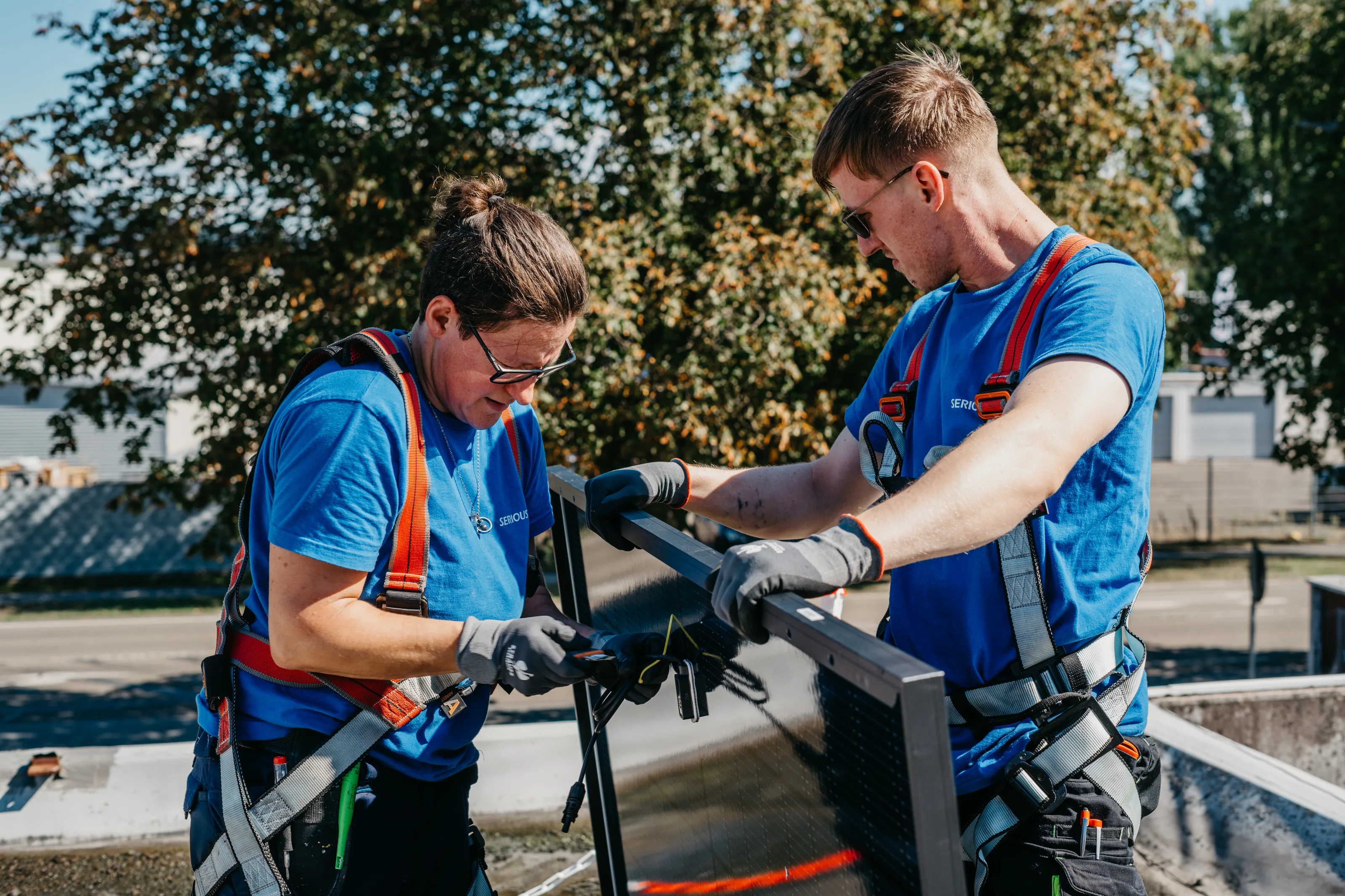 Zwei Monteure mit Auffanggurt setzen ein Solarmodul